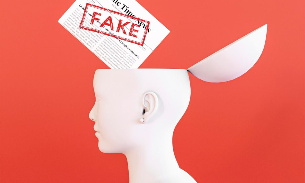 Ilustração mostra um jornal onde se lê a palavra Fake em vermelho e uma cabeça aberta, onde o conteúdo do jornal está sendo despejado, simbolizando como as fake news podem contribuir para reforçar ideologias e interesses