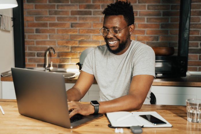 Imagem de homem negro profissional trabalhando em seu notebook, no texto sobre o tema: Quanto custa plano de saúde empresarial?