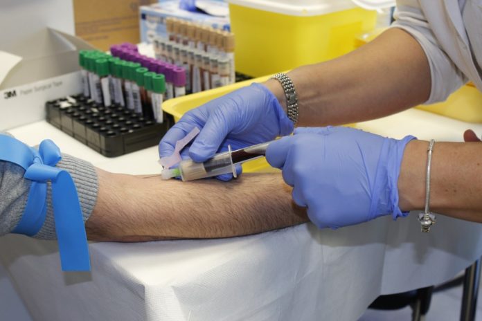 Imagem de médico colhendo sangue de paciente durante exame, presente no texto sobre cobertura parcial temporária (CPT) no blog da Sami.