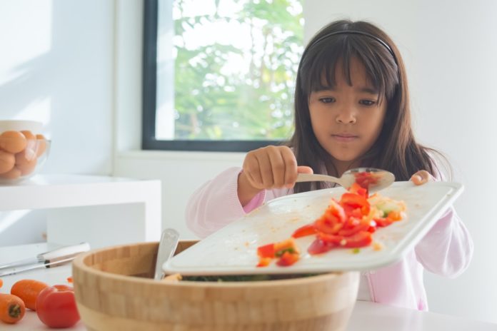 Imagem de criança preparando uma receita com tomates frescos, presente no texto no blog da Sami sobre o tema: Plano de saúde cobre nutricionista?