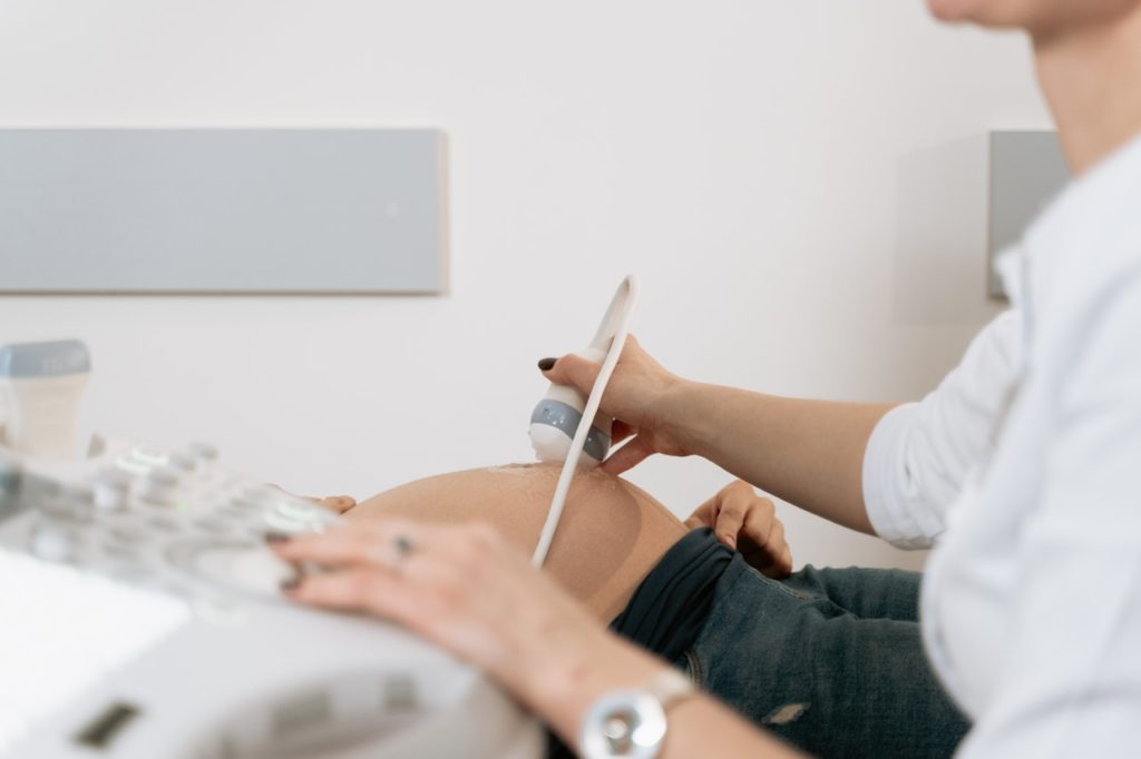 Imagem de médica realizando exame ultrassom em mulher gestante, presente no texto sobre plano de saúde com obstetrícia no blog da Sami