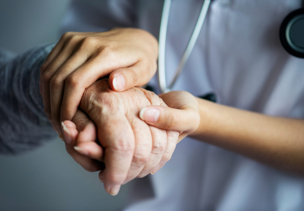 Imagem de enfermeira segurando a mão de paciente idoso, presente no texto do blog da Sami que explica o papel do(a) enfermeiro(a) na Atenção Primária à Saúde