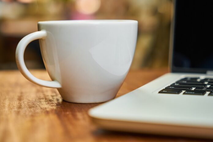 Imagem de xícara de café junto a notebook, presente no texto do blog da Sami que trata sobre clima organizacional e como isso afeta a saúde dos colaboradores