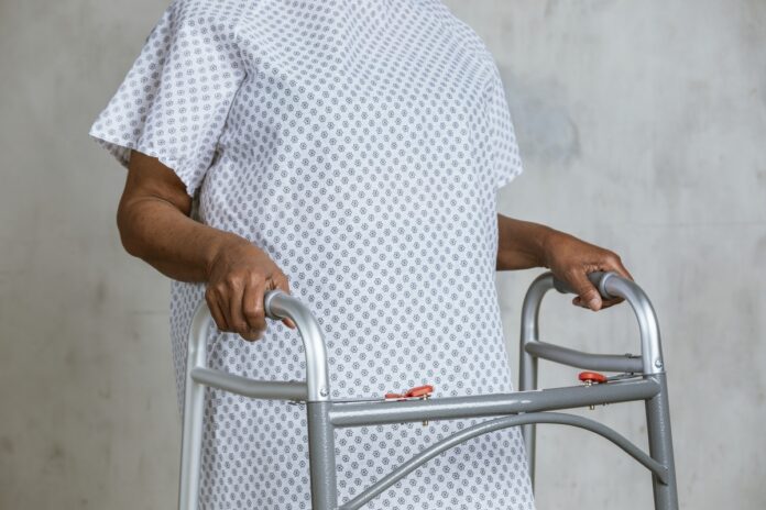 Imagem de paciente madura andando no hospital de andador, presente no texto do blog da Sami que responde à dúvida: plano de saúde cobre fisioterapia?
