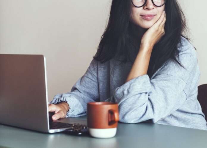 Imagem de empreendedora trabalhando de casa, tomando um chá e feliz, presente no texto do blog da Sami que trata da relação entre ansiedade e empreendedorismo