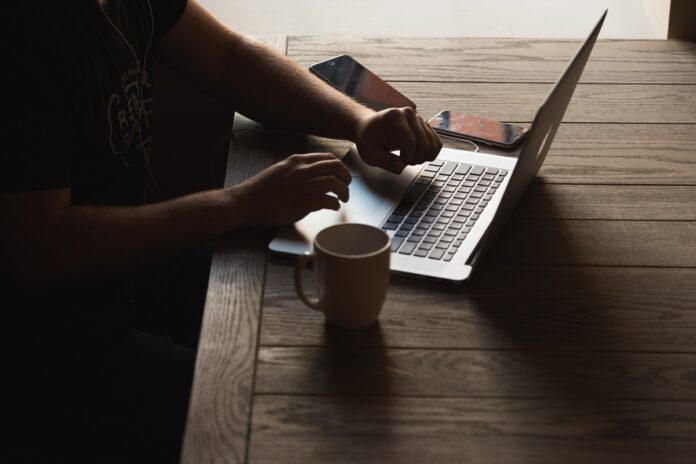 Imagem de jovem empreendedor trabalhando enquanto toma café, presente no texto do blog da Sami que trata sobre a importância do sono para empreendedores