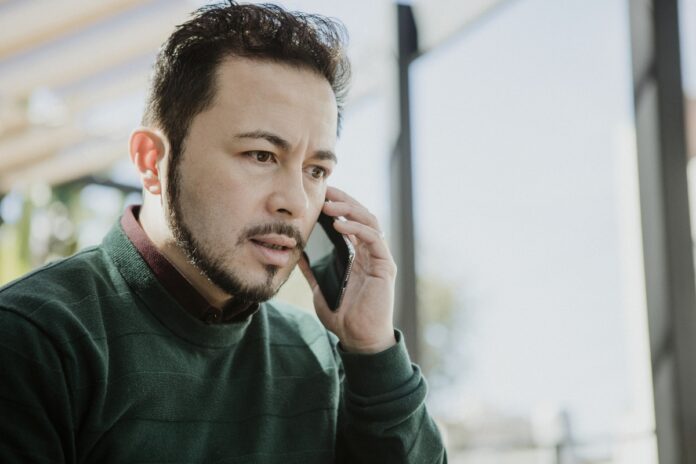 Imagem de homem estressado falando no telefone com sua nova operadora de plano de saúde, presente no texto do blog da Sami que responde à dúvida: 
