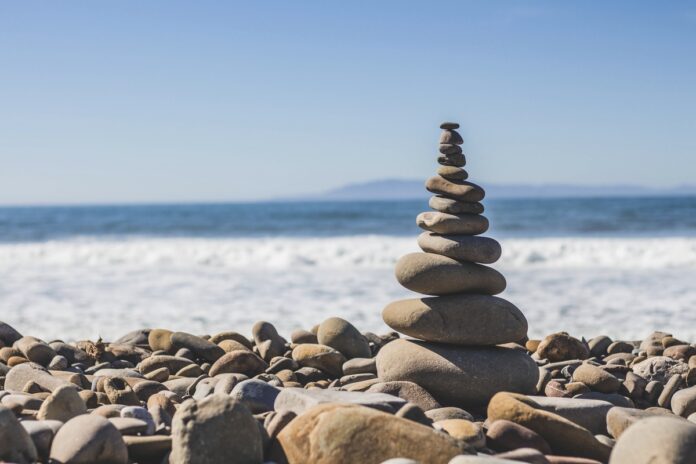 Imagem de pedras em equilíbrio numa praia, presente no texto do blog da Sami sobre meditação, seus tipos, benefícios e como começar